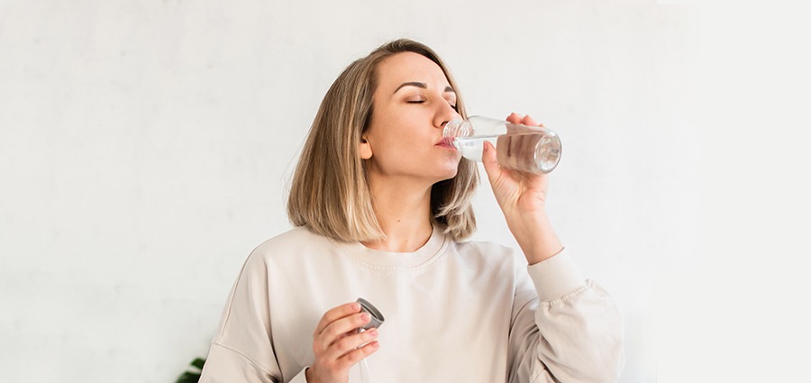 woman with a dry mouth drinking water after smoking alien og weed. buy weed online in Canada.