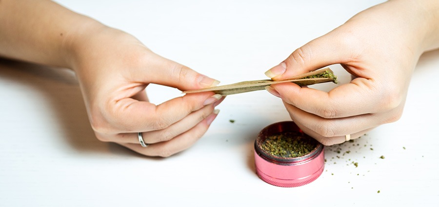 woman with weed and a grinder rolling a joint after buying weed online from My Green Solution online dispensary in Canada for weed online.