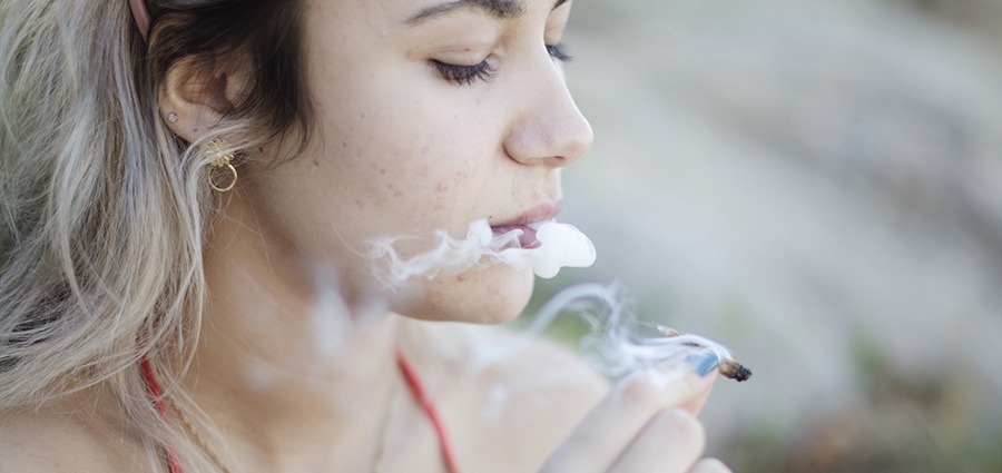 Female smoking a joint of BC cannabis outside. online dispensary. weed shop. indica strains. sativa strains.