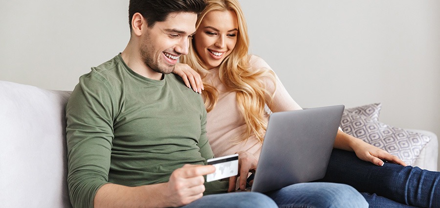 Cheerful couple buying weed online with a credit card on a lap top from My Green Solution online dispensary and mail order marijuana weed store. Buy weed online Canada.